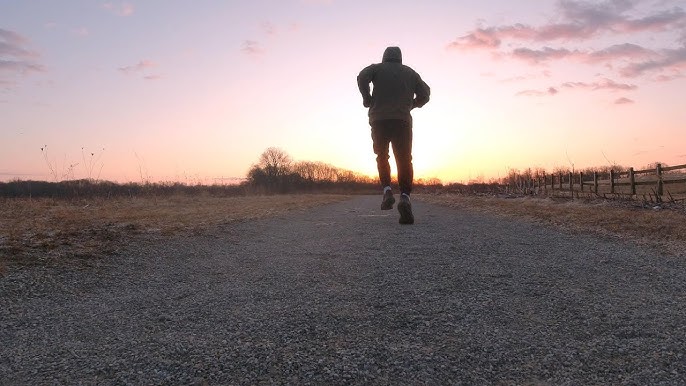 Person jogging on a scenic trail at sunrise, representing an active and energized lifestyle